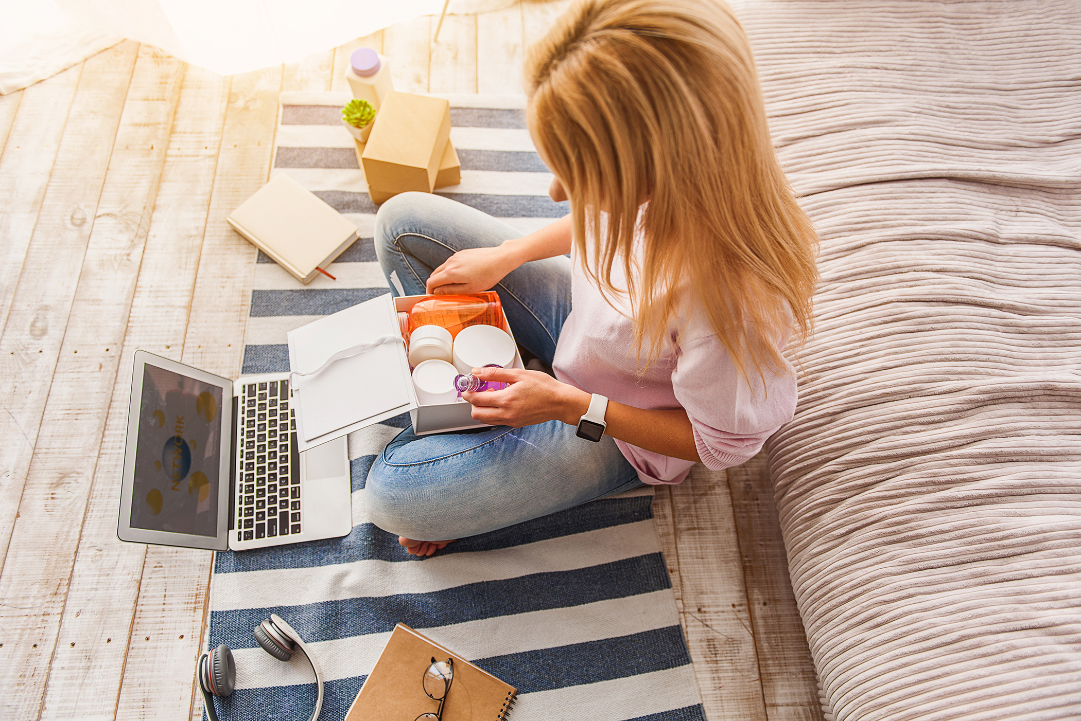 woman opening online order of beauty products from salon whilst on laptop