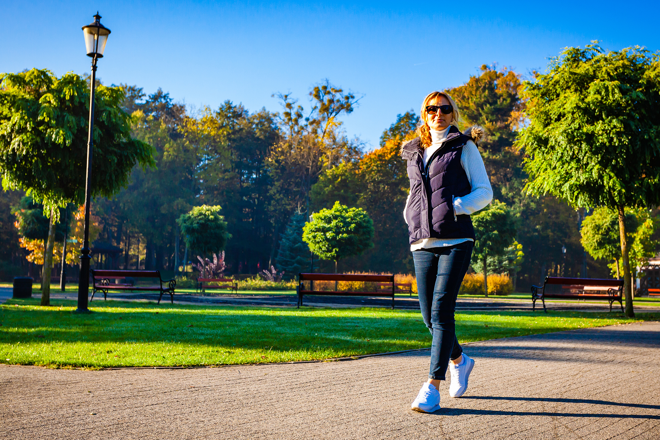Woman walking park trees on sunny day