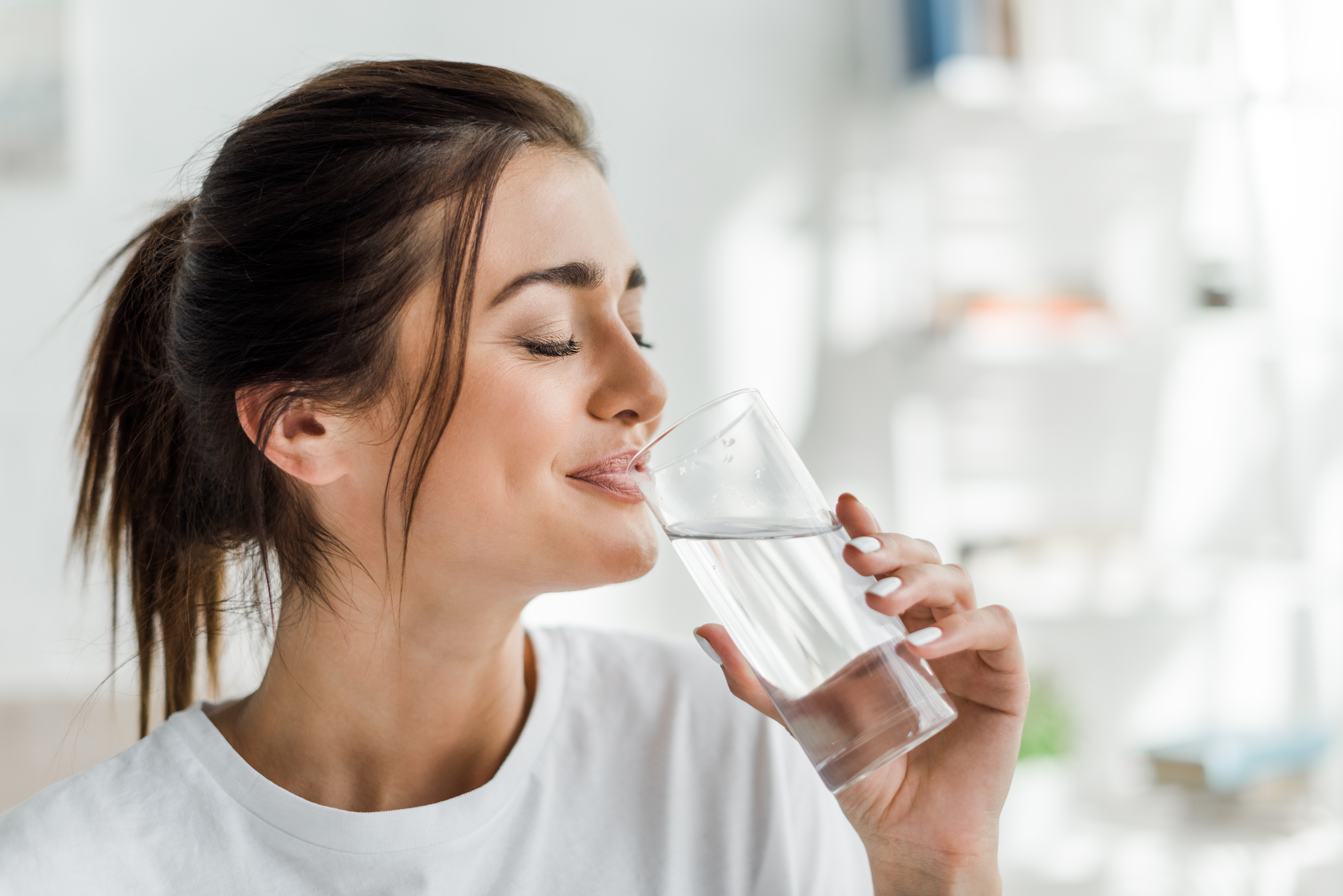 Woman in white T-shirt drinking a glass of water