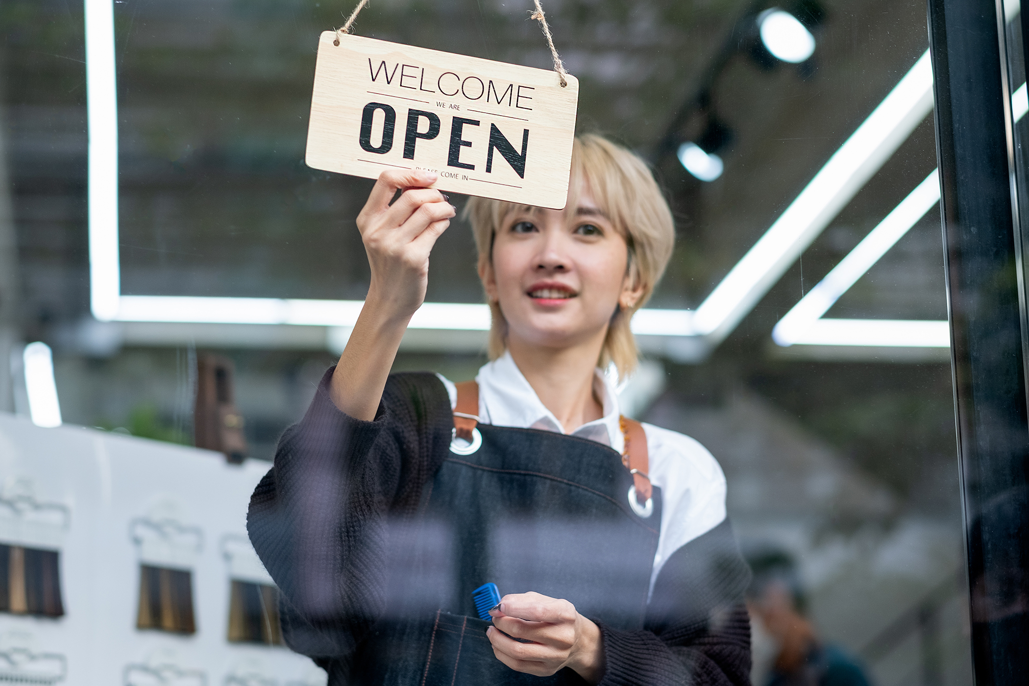 Beauty therapist with open sign on salon door