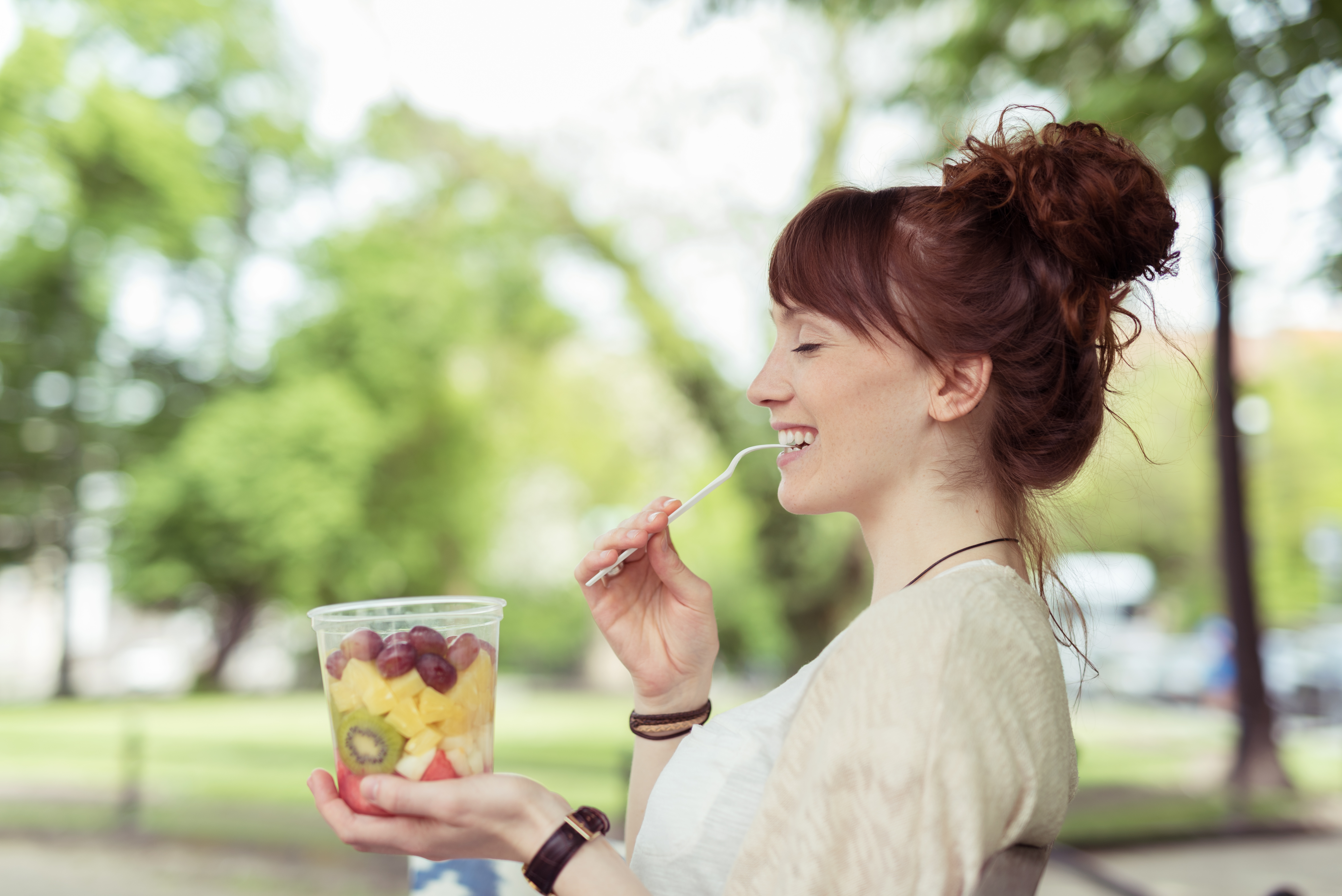 Woman eating fruit salad outside